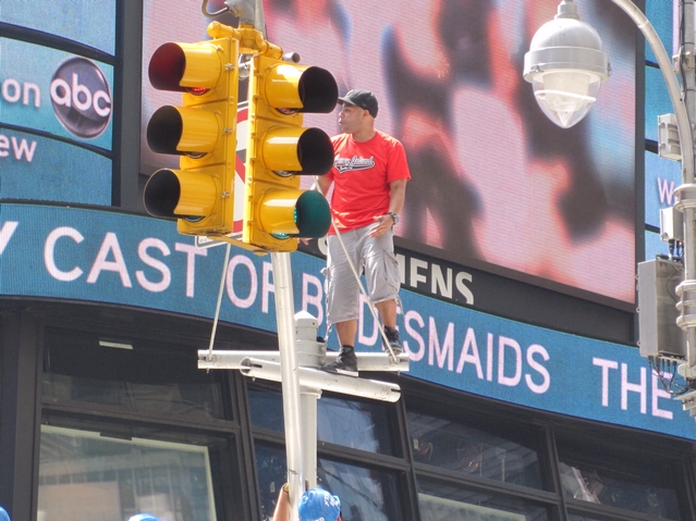 Unidentified man stands atop a traffic signal pole while rapping in Times Square Tuesday morning.