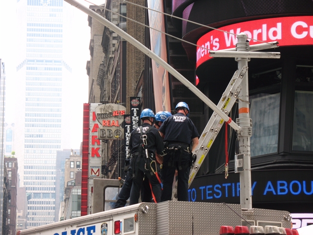 Police arrest man after he climbs down from atop a traffic signal post in Times Square on Tuesday.