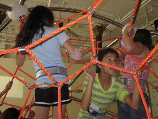 Kids pull themselves up the Climb-A-Thon structure, chasing blinking lights.