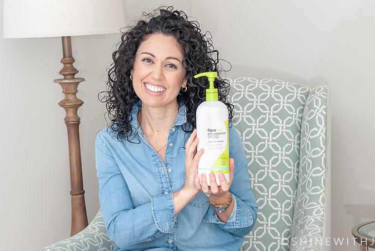 10 Reasons to Try DevaCurl One Condition Original curly haired woman holding DevaCurl product on chair
