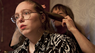 Barbara Cullison does her daughter Audrey's hair. Audrey, who is autistic, risks losing her Medicaid waiver services because of state budget cuts. 

