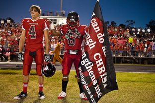 As two Kountze football players prepare to play a game on Oct. 5, 2012, one holds a banner with a Bible verse. A Hardin County judge recently ruled that the high school's cheerleaders can continue to display signs with religious messages at football games.