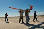 Micheal Cincienne of Absolute Aerospace and Texas A&M Corpus Christi, engineering student Adam Ersepke, and lab coordinator Jack Edward Esparza carry the University’s RS-16 unmanned aerial vehicle, otherwise known as a drone, back to the  command center after a test flight over the Kennedy Ranch near Sarita, Texas on January 18, 2013.