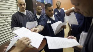 An inmate returns tests to his peers during a break from class. Inmates are regularly tested as a part of their academic business curriculum, part of which is modeled on Harvard MBA classes.