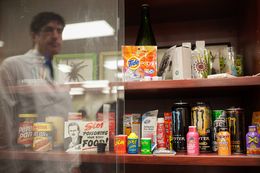 Recalled products, natural threats, choking hazards, and items that could cause emergencies when large amounts are ingested by children, are displayed at the South Texas Poison Center in San Antonio. Miguel Fernández, managing director of the center, is reflected in the display case glass.