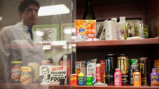 Recalled products, natural threats, choking hazards, and items that could cause emergencies when large amounts are ingested by children, are displayed at the South Texas Poison Center in San Antonio. Miguel Fernández, managing director of the center, is reflected in the display case glass.