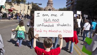 A kindergarten-age schoolboy walks up Congress Ave for a Save our School's rally on February 23rd, 2013