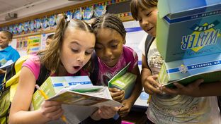 Three students at Bayless Elementary in Lubbock, Texas, consult a water usage chart after being presented with water conservation information and Waterwise kits by the High Plains Underground Water District.