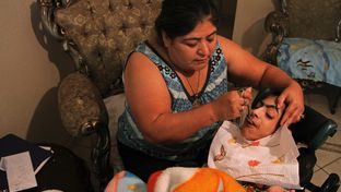 Maria Figueroa feeds Antonio Fuentes, 28, who has cerebral palsy and cannot speak. Figueroa has been Fuentes' health care provider for the past eight years.