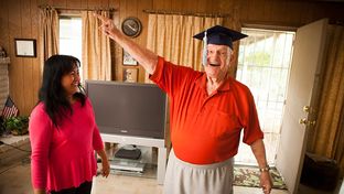 Robert Titus tries on his graduation cap with the help of his wife, Jennifer, in his Houston home on Nov. 26, 2012. Titus recently earned an online degree in marketing managment from WGU Texas.
