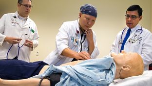 Third-year medical student Summer Scavone (middle) tries to listen to the SimMan's lungs for wheezing.