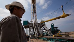 A worker waits to load a piece of pipe, or casing, that will be lowered into the well at a Chesapeake Energy drill site in Dimmit County, Texas in the Eagle Ford Shale.