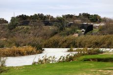 The Rio Grande and a towering border fence separate Eagle Pass, Texas from Piedras Negras, Mexico, Saturday, February 4, 2012.