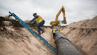Water pipeline crew members prepare for the laying of the next section of the 60-mile-long chain running near Eden, Texas.