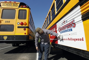 Eanes ISD school bus mechanic Chase Roberts washes the dirt off the advertising on Eanes ISD school buses in Westlake, Texas Tuesday February 14, 2012.