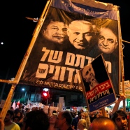 Protests with sign (front) in Hebrew reads: "Bibi go home (the petrol on us)", referring to Netanyahu. R