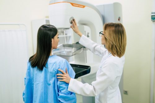 A nurse practitioner sets up a mammography unit for a patient.