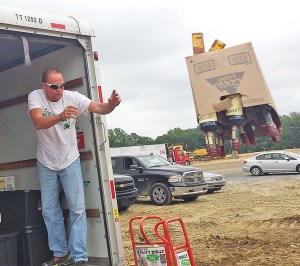 Delaware Alcohol and Tobacco Enforcement agent Jack Renaud heaves bottles of liquor to be crushed. (Photo credit: Delaware State News/Craig Anderson)