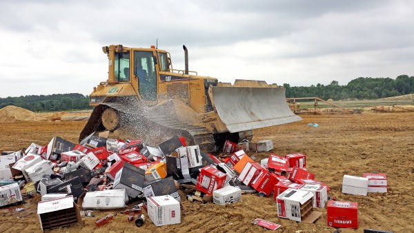 A bulldozer pulverizes a pile of confiscated liquor bottles and cans on Friday afternoon at the Central Solid Waste Management Center Sandtown landfill near Felton. (Photo credit: Delaware State News/Craig Anderson)