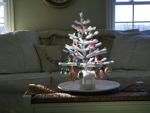 A feather Christmas tree sits atop a coffee table/ bench Feather Christmas Trees at MaisonDecor