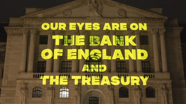 Yellow text reading "Our eyes are on the Bank of England and the Treasury' being projected onto the Bank of England at night-time
