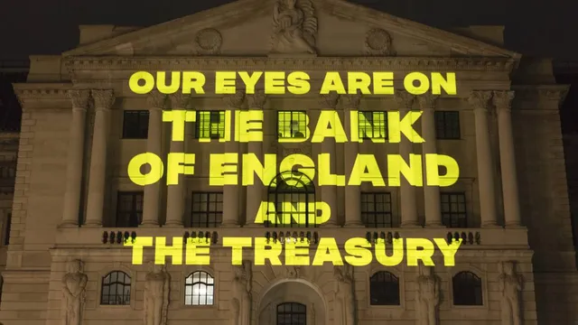 Yellow text reading "Our eyes are on the Bank of England and the Treasury' being projected onto the Bank of England at night-time