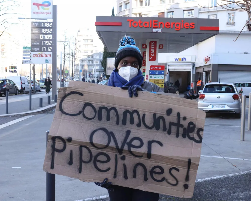 Anti EACOP protester holding sign saying 'Comunities over pipelines'