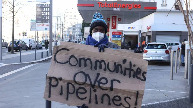 Anti EACOP protester holding sign saying 'Comunities over pipelines'