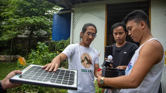 Three men construct a portable solar planel during a community-centred energy project in Tacloban, Philippines