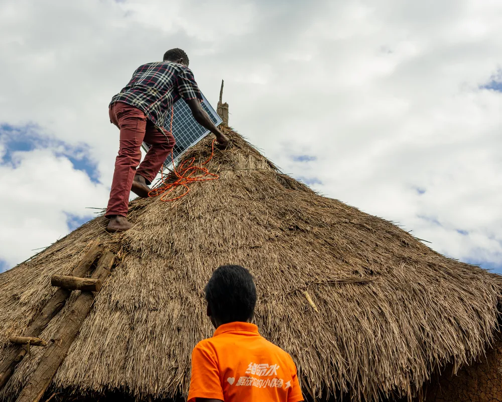 Locals install a solar panal on a hut.
