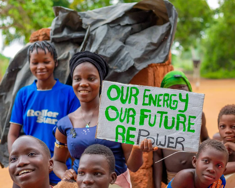 Woman and children facing the camera holding a sign saying our energy, our future