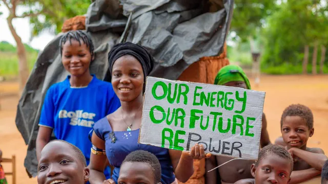 Woman and children facing the camera holding a sign saying our energy, our future