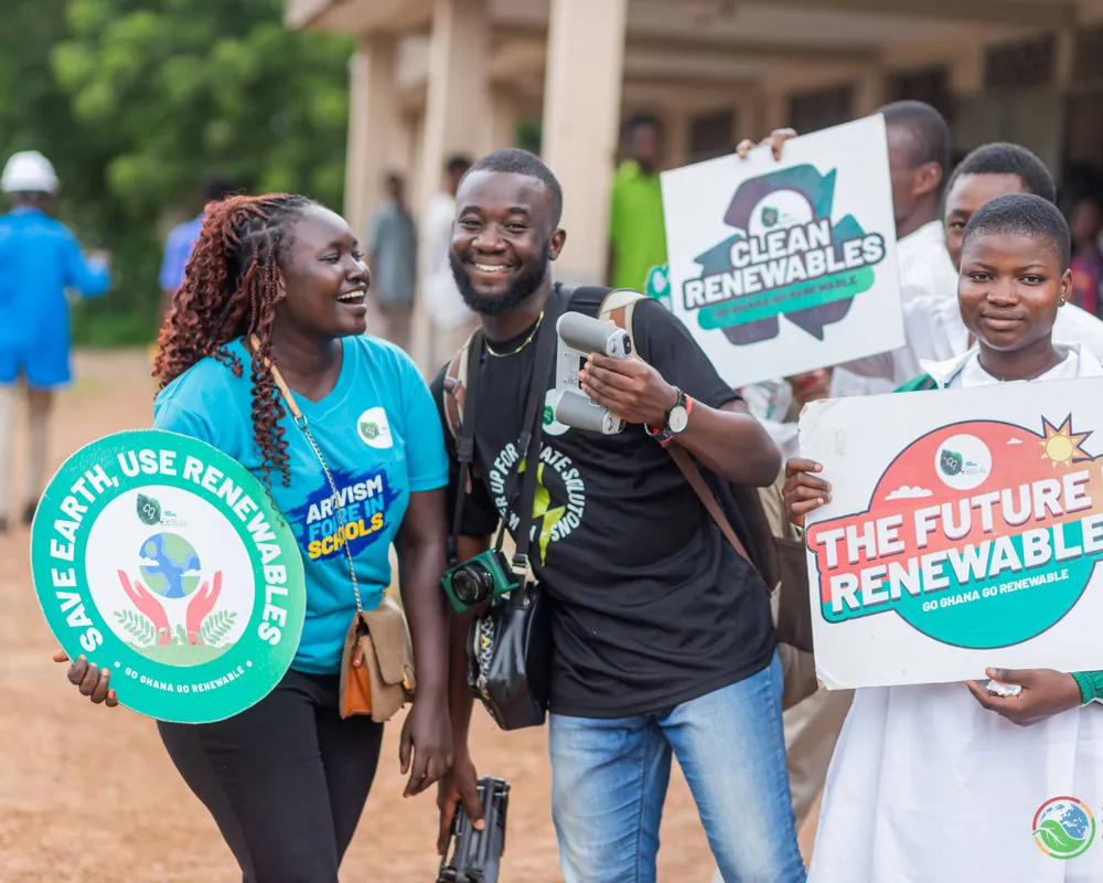 People smile at the camera holding banners reading the future is renewables