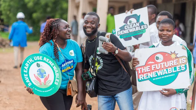 People smile at the camera holding banners reading the future is renewables