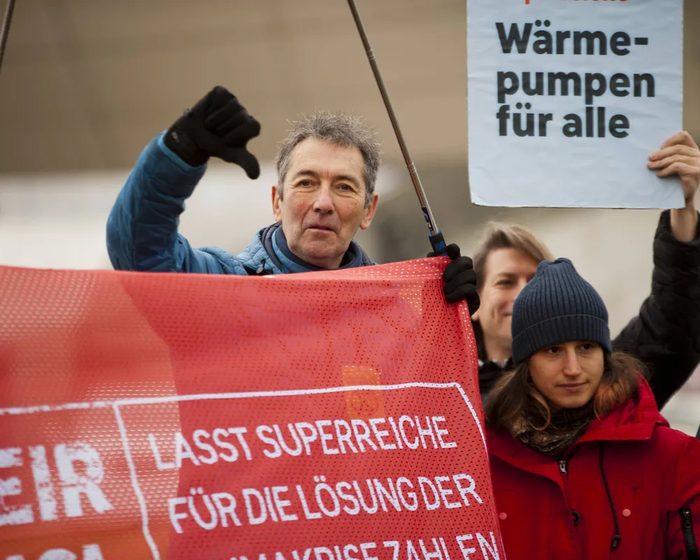 Aktivist*innen halten einen Banner mit 'Lasst Superreiche für die Lösungen der Klimakrise zahlen".