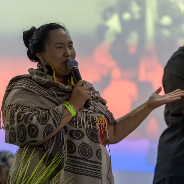Indigenous activist speaking into microphone during gathering session.
