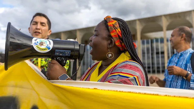 An activist in colorful attire speaks into a megaphone at action.