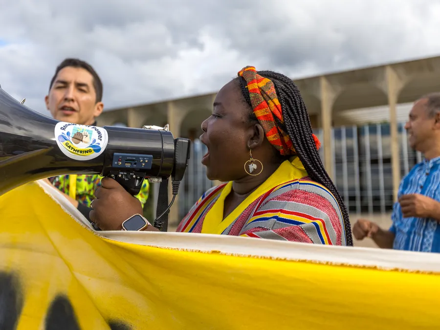 An activist in colorful attire speaks into a megaphone at action.