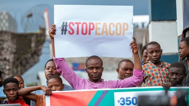 Protestors hold a StopEACOP sign