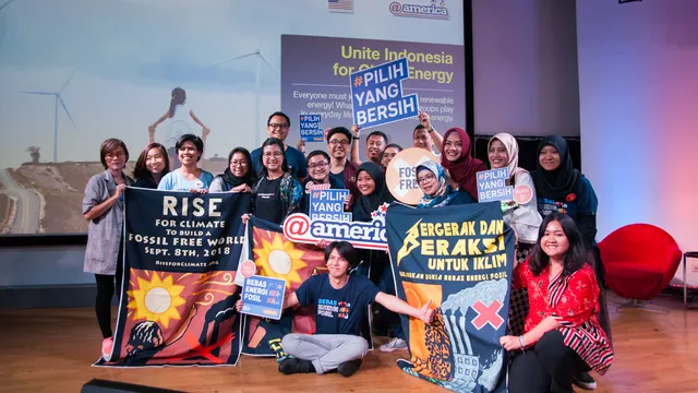 A group of climate activists in Indonesia poses with banners promoting renewable energy and fossil fuel-free future. They hold signs advocating for clean energy choices during a presentation event about sustainable energy.