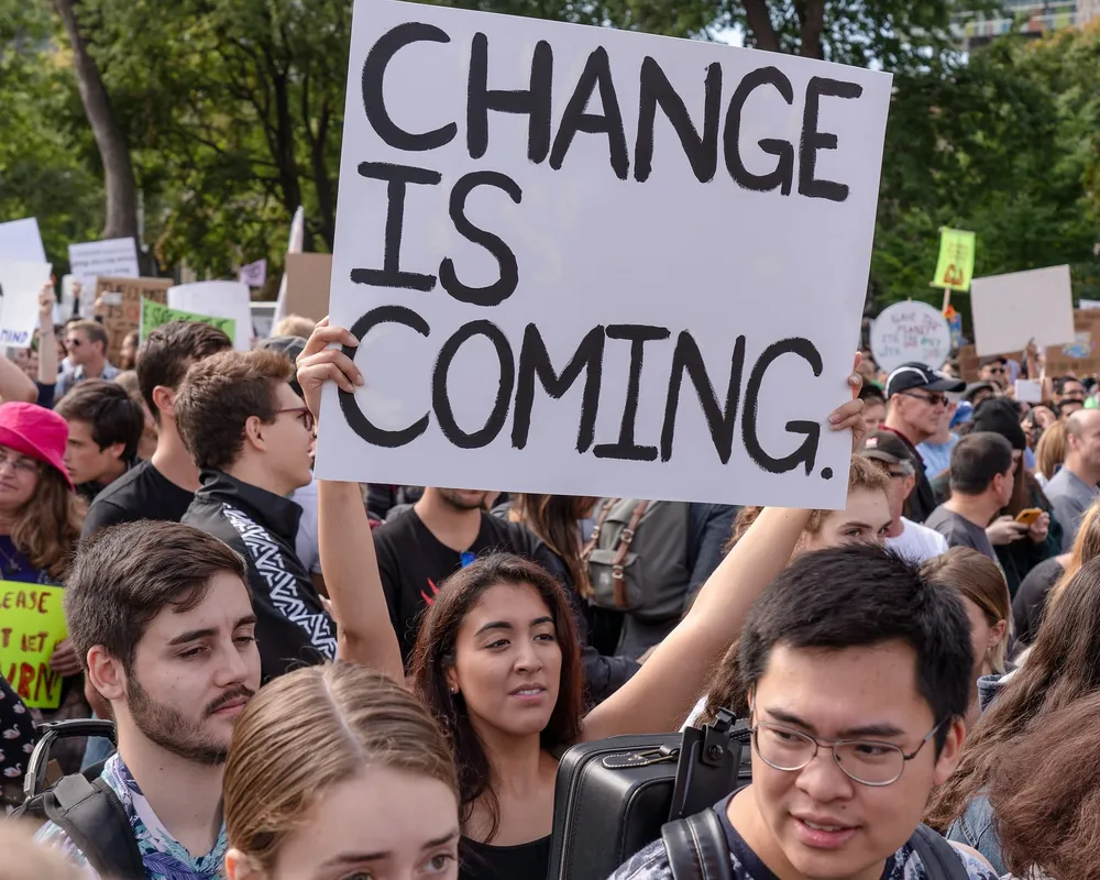 A young woman holding a sign that reads "Change is Coming"