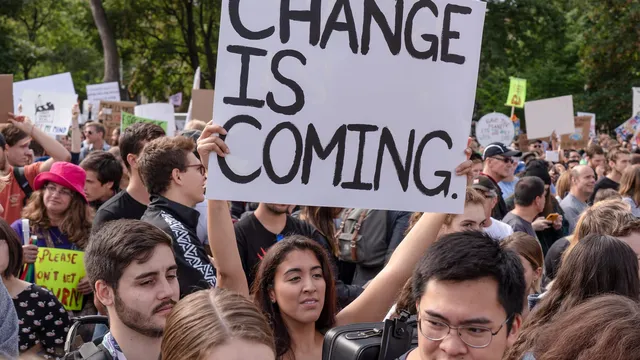 A young woman holding a sign that reads "Change is Coming"
