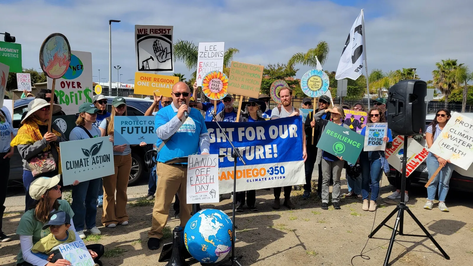 Photo shows a group of climate activists holding signs saying things like "fight for our future" and "hands off the earth." Some of them are wearing t-shirts that say SanDiego350. 