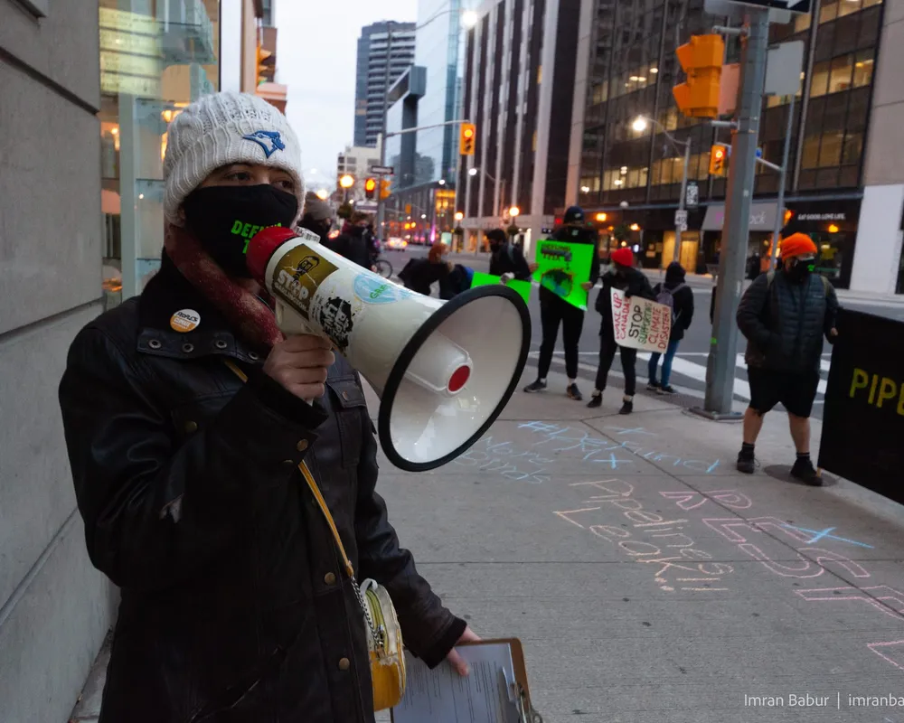 A protestor speaks through a megaphone while wearing a mask