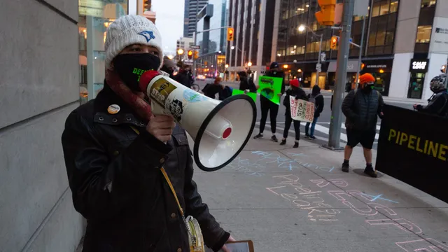 A protestor speaks through a megaphone while wearing a mask