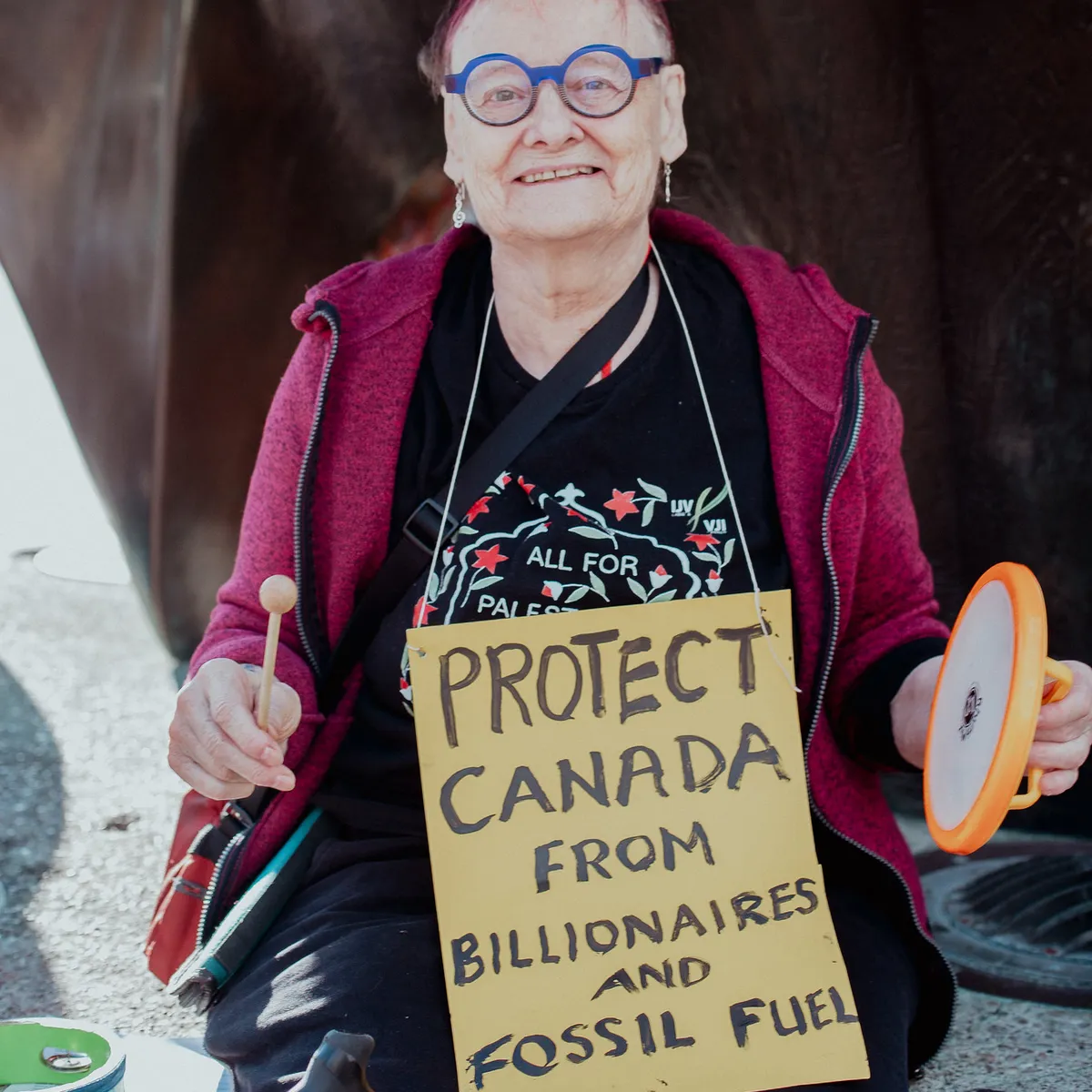 Older woman with sign that read "protect Canada from billionaires and fossil fuels"