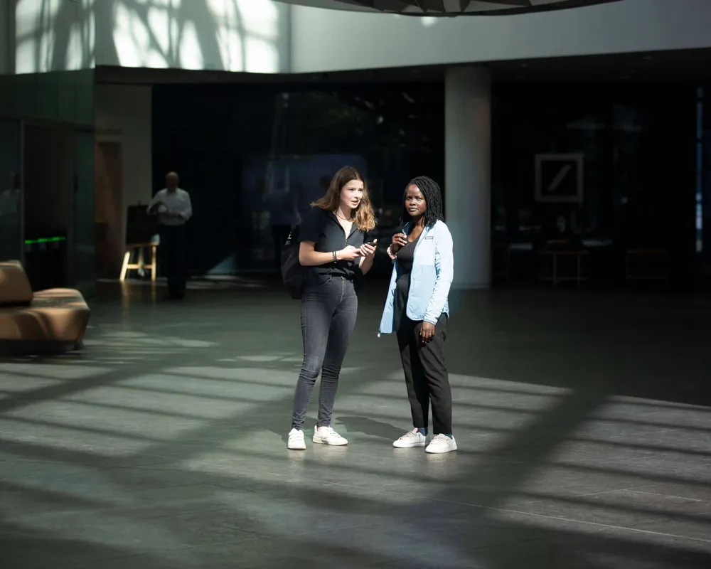 Luisa Neubauer und Evelyn Acham stehen in der Zentrale der Deutschen Bank