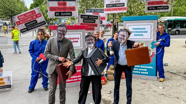 Activists dressed up as billionaries with briefcases and a champagne bottle, with people with a petrol pump prop behind them.