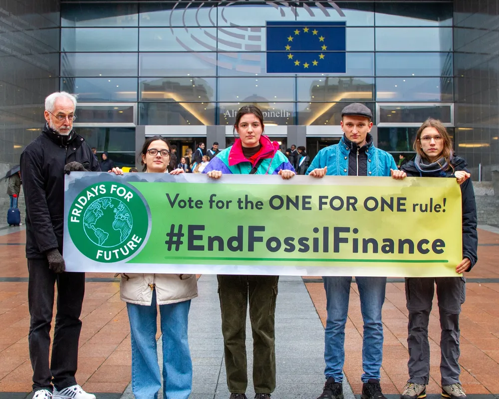 Aktivist*innen stehen vor dem EU Parlament mit einem Banner, auf dem #EndFossilFinance steht.