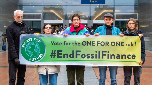 Aktivist*innen stehen vor dem EU Parlament mit einem Banner, auf dem #EndFossilFinance steht.